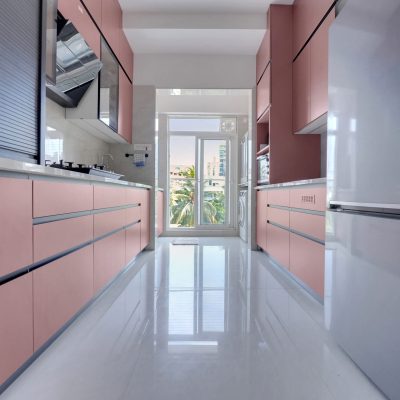 Modern pink modular kitchen with sleek handleless cabinets, white quartz countertops, built-in oven, glass display cabinets, and minimalist contemporary interior