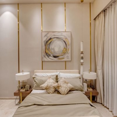 Modern luxury bedroom with beige interiors, gold vertical wall accents, upholstered bed, and elegant bedside tables.