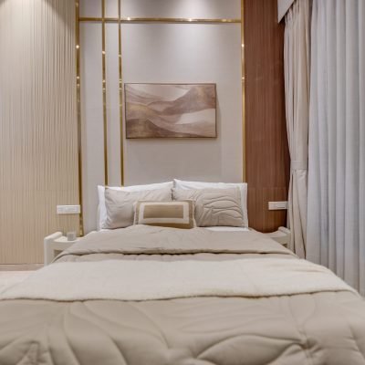 Modern beige bedroom with upholstered bed, gold accent wall, wood paneling, and sheer curtains.